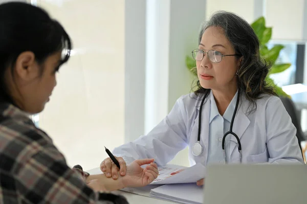 专业的亚洲资深女医生在她倾向的办公室对病人进行检查 检查病人手上的脉搏 医疗概念 — 图库照片