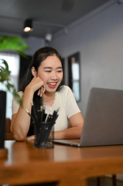 Portre, neşeli genç Asyalı bayan arkadaşlarıyla oturma odasındaki dizüstü bilgisayardan konuşmaktan hoşlanıyor..