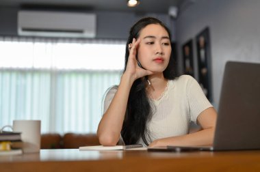 Çekici ve kendine güvenen Asyalı bir kadın oturma odasında çalışıyor, dizüstü bilgisayarında projesini planlıyordu..
