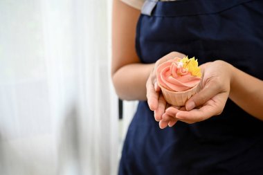 Yakından bakınca elinde taze pişmiş kek tutan bir kadın görülüyor.  