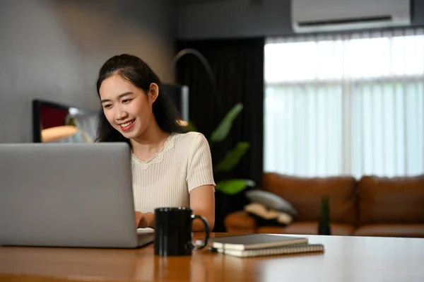 stock image Happy young Asian female college student using portable laptop computer to manage her homework in her modern living room.