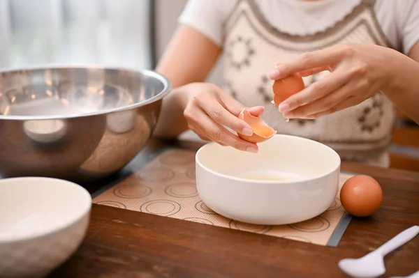 女性は卵を割り 卵黄を卵白から分離し 台所でカップケーキの成分を調製する 切り取られた画像 — ストック写真