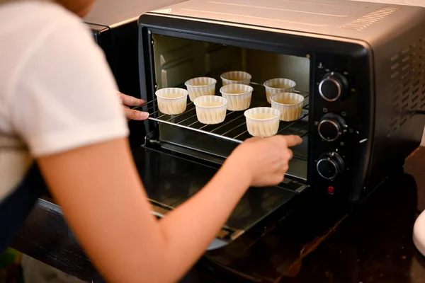 オーブンに新鮮なカップケーキのトレイを入れて女性のパン屋 オーブンでカップケーキを焼く カップケーキのレシピコンセプト クローズアップ画像 — ストック写真