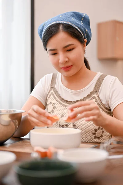 魅力的な若いアジアの女性は 卵と卵の黄身を白い卵から分離し 台所でカップケーキの成分を準備します カップケーキのレシピコンセプト — ストック写真