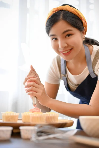 美しい女性はカップケーキを作ります キッチンでクリームとカップケーキを飾る — ストック写真
