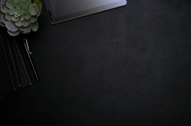 Metninizi göstermek için dijital tablet, kalem, dekor bitki ve kopya alanı ile modern stil siyah çalışma alanı üst görünümü.