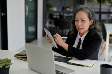 Profesyonel ve başarılı Asyalı iş kadını ekibiyle çevrimiçi toplantı veya konferans yapıyor, çalışanlarını çevrimiçi olarak eğitiyor, dizüstü bilgisayar kullanıyor, ofiste çalışıyor..