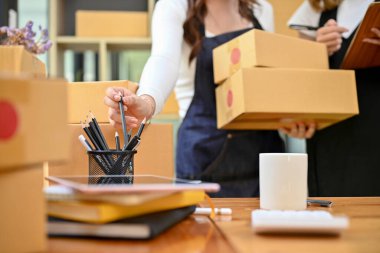 İki kadın küçük işletme girişimcisi depoda birlikte çalışıyorlar, posta dağıtım şirketine gönderilecek kargo kutularını hazırlıyorlar. kırpılmış resim