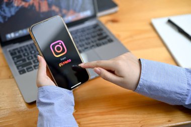 Chiangmai, Tayland - 23 Ağustos 2022: Ekranda Instagram pankartıyla akıllı telefon tutan bir iş kadını ya da kadın eli. Cep telefonunda Instagram uygulaması kullanan bir kadın. yakın plan resim