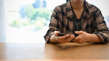 Kafede otururken akıllı telefonunu kullanan fanila gömlekli Asyalı bir kadın. metin, mesaj, sohbet veya sosyal medya