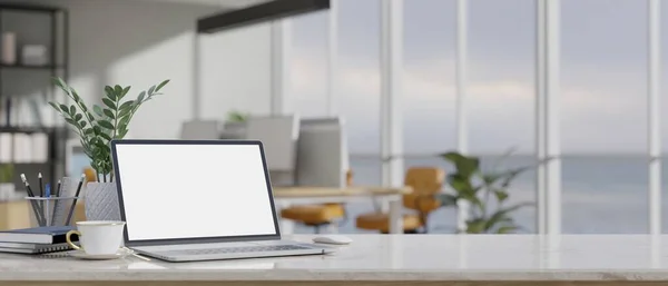 现代写字台办公空间配备笔记本电脑空白屏幕模型 咖啡杯 文具和复印空间模糊的现代办公室背景 3D渲染 3D说明 — 图库照片