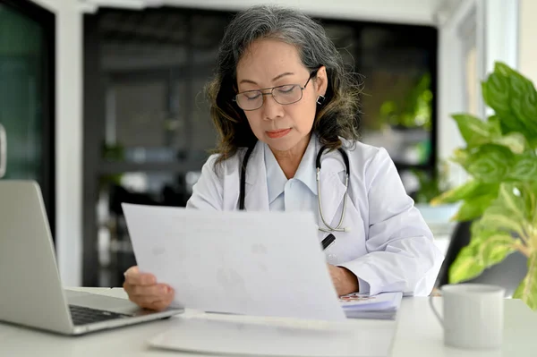 亚洲老年专业女医生 专注于医学研究 在医生办公室的办公桌前工作 — 图库照片