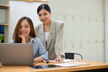 Portre, iki çekici ve başarılı Asyalı iş kadını ofiste birlikte çalışıyorlar..