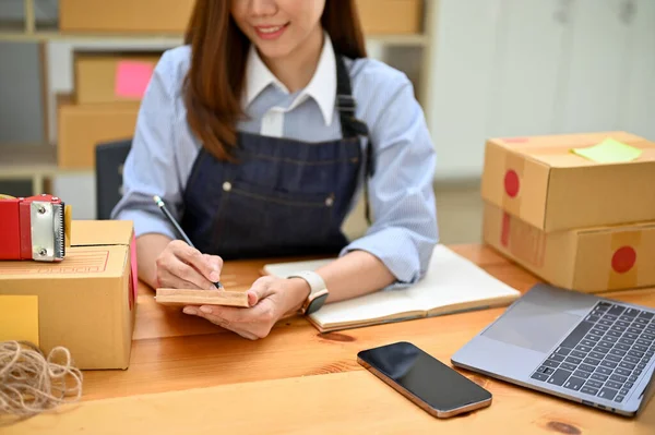 Başarılı genç Asyalı bayan küçük online girişimci siparişlerini kontrol ediyor ve nakliye paketlerini hazırlıyor. kırpılmış resim