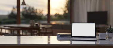 Çalışma alanı masa üstü dizüstü bilgisayar beyaz ekran maketi, kahve fincanı, kitap ve fotokopi alanı çağdaş ve lüks oturma odasının bulanık arka planına karşı. 3d görüntüleme, 3d illüstrasyon