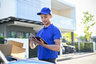 Genç profesyonel teslimatçı müşteriye göndermeden önce paketi tabletle kontrol ediyor. nakliye konsepti, kurye