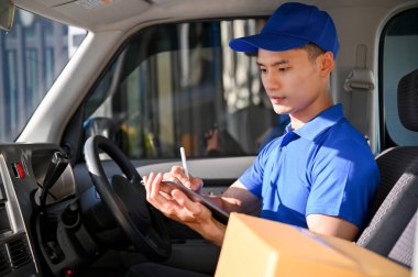 Paketi müşterilere teslim etmeden önce genç teslimatçı siparişleri tabletle kontrol ediyor. Kurye, nakliye rakunu