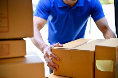 Paketleri müşterilere teslim etmeden önce mavi üniformalı teslimatçının paketleri düzenleme görüntüsünü kapat