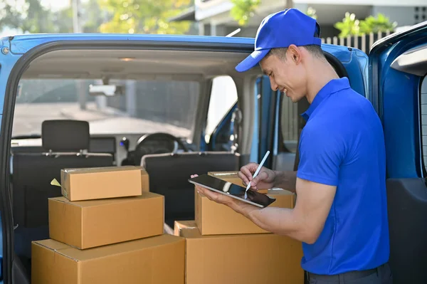 送货员穿着蓝色制服在平板电脑上检查包裹的近景 然后再发给客户 — 图库照片