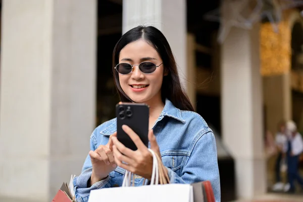Genç Asyalı Kadın Akıllı Telefon Tutuyor Alışveriş Merkezinden Alışveriş Yaparken — Stok fotoğraf