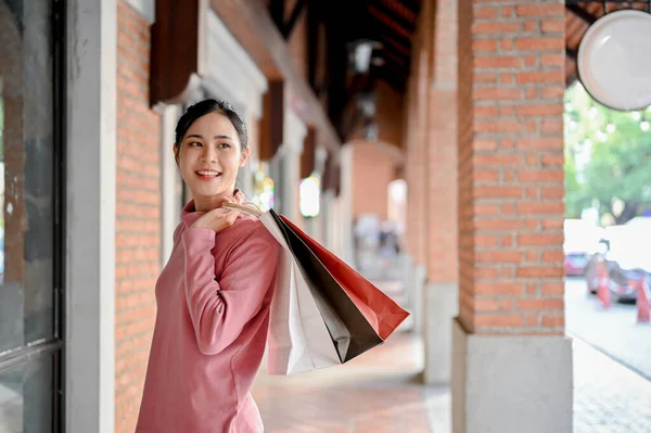 ショッピングバッグを持ったカジュアルな服装でアジアの若い女性を自信を持って 週末に街のショッピングセンターで買い物を楽しむ — ストック写真