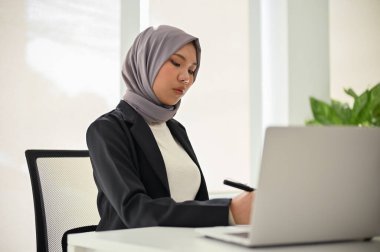 Profesyonel Asyalı Müslüman iş kadını ya da kadın yönetici, iş görevlerine yoğunlaşıyor, özel ofisinde çalışıyor..