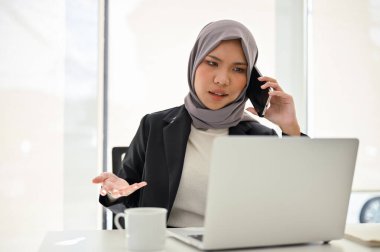 Mutsuz ve profesyonel Asyalı Müslüman iş kadını veya projenin sonucundan memnun olmayan bayan yönetici telefonda çalışanına şikayette bulunuyor..