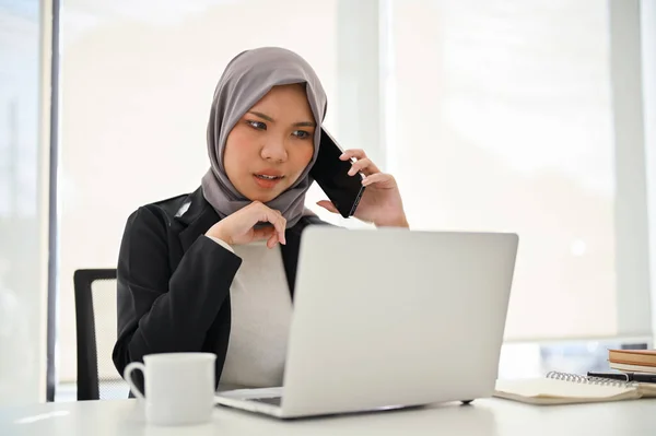 Professional Asian Muslim businesswoman unsatisfied with the project's outcome, complains to her employee over the phone.