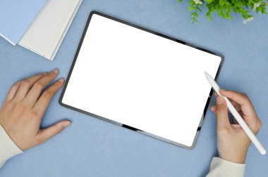 Stylus kalem kullanan bir kadının üst görüntüsü, minimum mavi çalışma alanında dijital tablet üzerine çizim. tablet beyaz ekran modeli