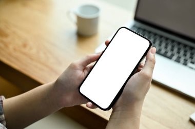 Akıllı telefon beyaz ekran modeli modern ofis masasında bir kadının elindedir. en üstteki görünüm, yakın plan görüntü