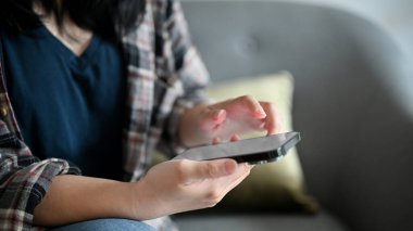 Flanel gömlekli bir kadın kahve dükkanında dinlenirken arkadaşlarıyla sohbet etmek için akıllı telefonunu kullanıyor. kırpılmış resim