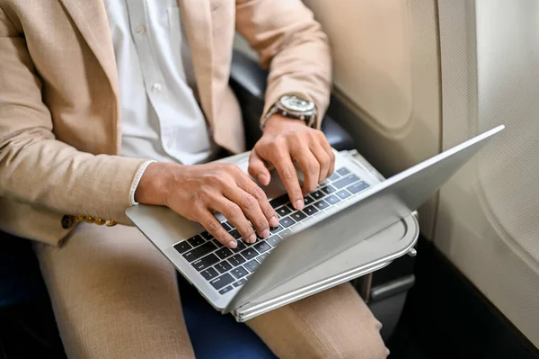 cropped, top view, A professional businessman or male CEO using a laptop computer, typing on the keyboard, managing his business tasks during the flight. Business people and transportation concept