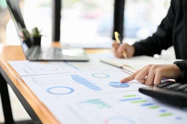 Profesyonel bir iş kadını ya da kadın bir finans analisti finansal raporunu işaret ederek ofisinde veri analizi yapıyor. yakın plan parmak konsepti