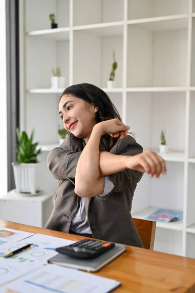 Portrait, Relaxed and chill Asian businesswoman or female boss stretching her arms after finish work at her office desk.