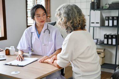 Profesyonel Asyalı kadın doktor teşhis koyar ve klinikteki hastasına tedavi ve ameliyat planlarını açıklar..