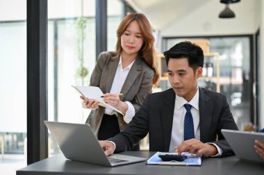 Profesyonel Asyalı iş adamı asistanıyla birlikte ofiste çalışıyor. iş insanları konsepti