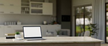 Close-up image, Laptop white screen mockup on white marble tabletop over blurred background of minimal bright home kitchen and living room. 3d rendering, 3d illustration