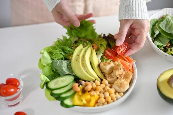 女性がお椀や植物性のサラダ野菜を混ぜ合わせ 豆腐をひよこ豆 トマト アボカドスライド キュウリ グリーンサラダで焼きます 食事のコンセプト — ストック写真