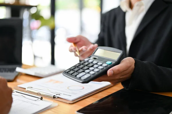 Professional male accountant or financial consultant showing a calculator with value of investment profit to his client. close-up image
