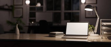 close-up image, Modern office workspace at night with low light from table lamp, laptop screen mockup, book, document tray and copy space on tabletop. 3d render, 3d illustration