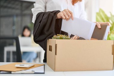 A businesswoman packing her stuff into a cardboard box at her office desk. quitting a job, career failure, unemployment, change a job.