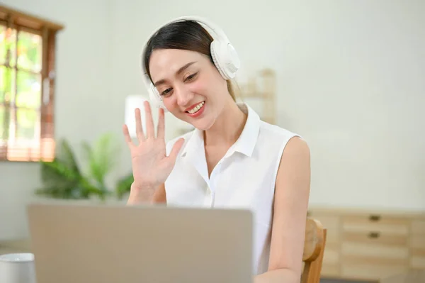 Attractive and charming millennial Asian businesswoman having an online meeting at home, work from home. A female online tutor teaching or tutoring her students via online meeting.