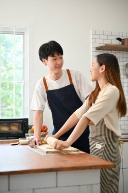 Joyful and lovely young Asian couple making dough, enjoy baking pastry in the kitchen together. boyfriend and girlfriend concept