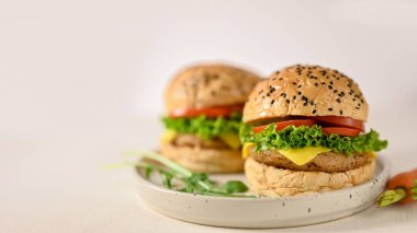 American fast food concept, Tasty beef burgers with fresh vegetables and cheese on minimal ceramic plate, white background.