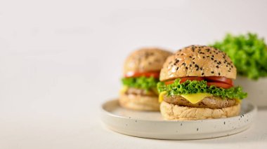 Tasty beef burgers with fresh vegetables and cheese on minimal ceramic plate, white background. American fast food concept