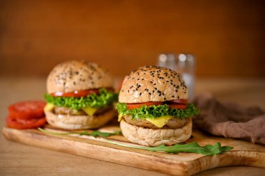 Fast food concept, Delicious beef burger with melting cheese, tomato slides, lettuce and special sauce. close-up image