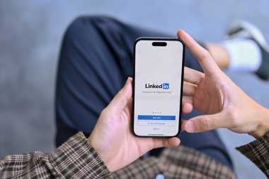 Chiang Mai, Thailand - Jan 31 2023: Top view of a man in casual clothes using LinkedIn website on his smartphone, Login or Sign in on LinkedIn platform. job, online resume