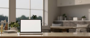 Bilgisayarlı beyaz ekran maketi, kitap, boyama araçları, dekor fabrikası ve arka plandaki bulanık modern yemek odasının üzerine kopyalama alanı olan çalışma alanı. 3d görüntüleme, 3d illüstrasyon