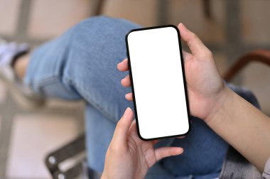 Top view of a female using her smartphone while relaxing in the backyard. phone white screen mockup for display your graphic.