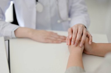 Close-up image of a female doctor holding a patient's hands, supporting and reassuring during the medical checkup. healthcare and medical concept